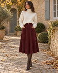 Woman wearing the Burgundy Corduroy Outfit: ivory chunky turtleneck sweater and burgundy corduroy A-line skirt