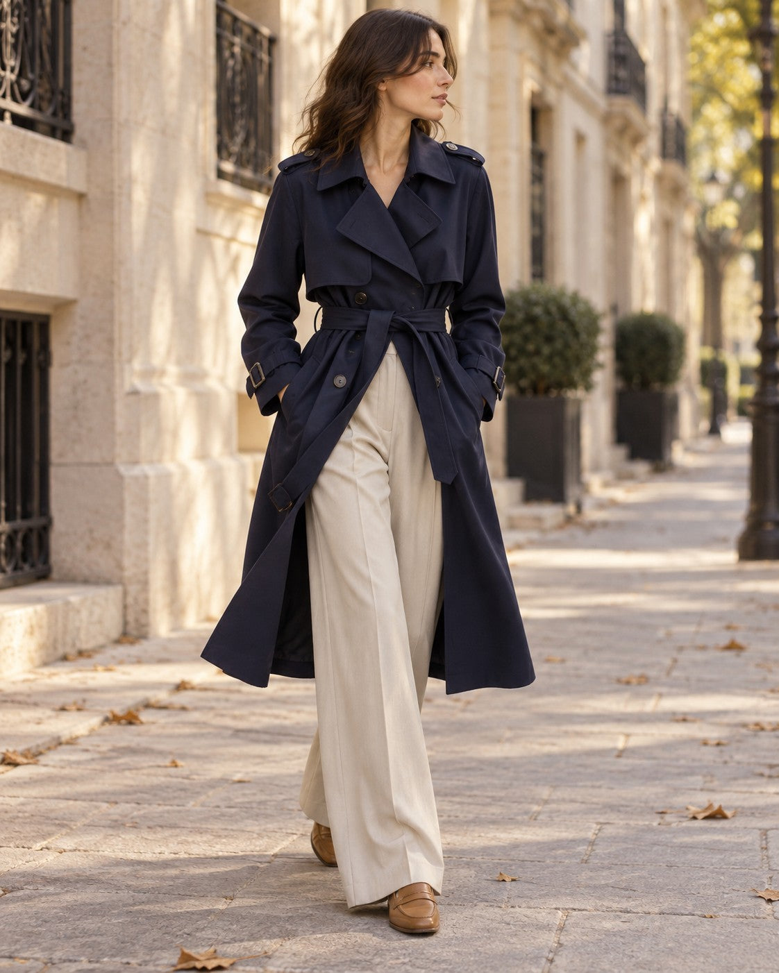 Woman wearing the Navy Trench Outfit: navy double-breasted belted trench and ivory pleated wide-leg trousers