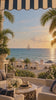 Beach club terrace at golden hour with a sailboat on the horizon
