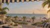 Beach club terrace at golden hour with a sailboat on the horizon