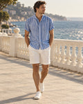 Man wearing the Seaside Stripe Shirt Outfit: French-blue stripe linen band-collar shirt and white pleated turn-up shorts